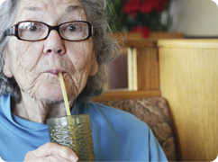 older woman drinking water through a straw