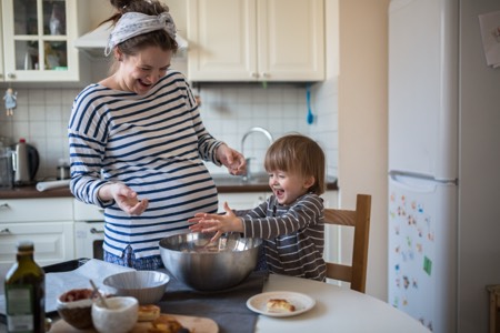 A pregnant woman and young child cooking