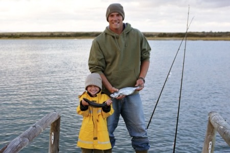 Man and young woman on a dock, both holding fish
